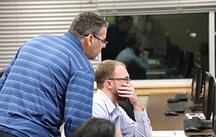 Male professor helping students in a computer lab