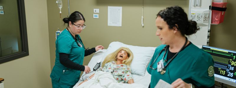 Female Nursing Students Beside a Patient