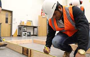 Male Student Marking Measurements On Wood