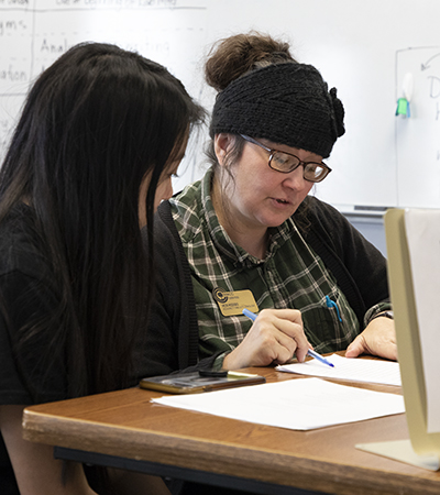 Mature female with glasses tutoring a young female student in writing