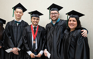 Group of four graduates smiling in their caps and gowns