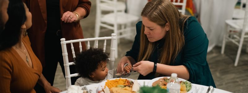 Woman Helping Feed a Child