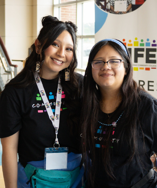 Two women smiling and wearing black shirts with "community" on them