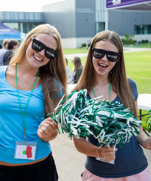 Two women in sunglasses waiving pompoms