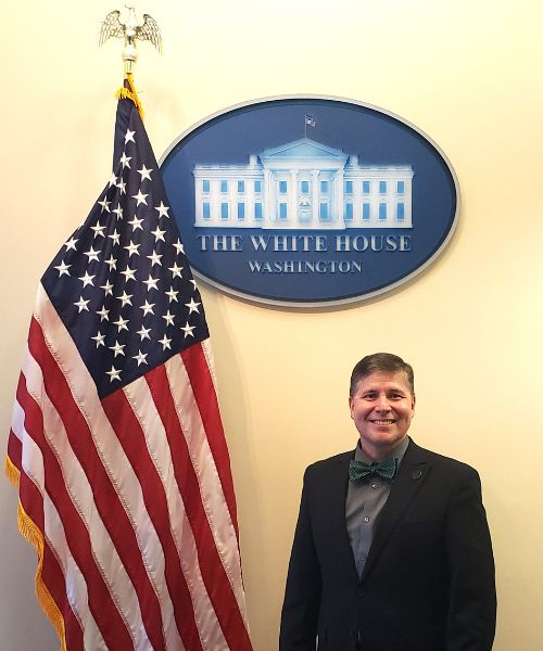 NWACC President Standing in Front of a White House Sign and American Flag