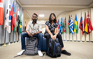 Two Students Sitting and Surrounded by Flags