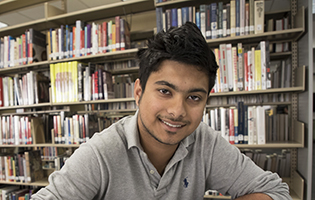 Young Hispanic male student smiling in the library
